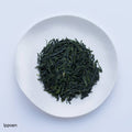 White plate of dark green prized high-grade loose leaf Ippodo Tea Ippoen gyokuro tea leaves on white table