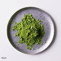 Loose green finely ground premium verdant green Japanese Ippodo Kuon Matcha tea powder on silver plate on white table