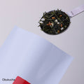 Stainless steel tablespoon measure of genmaicha green tea mixed with roasted rice scooped from red and white bag of Obukucha - thumbnail 3