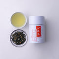 Can of Ippodo Tea Obukucha beside porcelain teacup of brewed Good Fortune tea and plate of loose green tea and roasted rice - thumbnail 5