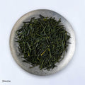 Ippodo Tea Uji Shincha sample depicting loose green needle-like rolled futsumushi tea leaves on silver plate on white table