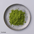 Bright green loose Japanese Ippodo Tea Tsukikage matcha powder on grey plate on white table