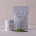 Lush green loose Ummon matcha powder by Ippodo Tea on small silver plate beside tin and resealable bag packaging options