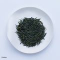Ippodo Tea Kumpu sencha sample depicting loose green needle-like rolled futsumushi tea leaves on white plate on white table 