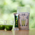 Funny cartoon package of Uji-Shimizu by Ippodo Tea beside one green to-go matcha packet and two glasses of vivid iced matcha
