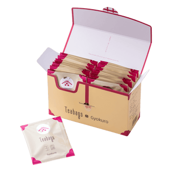 Open cream box containing 25 individually wrapped Gyokuro Teabags beside one teabag packet with pink corners and Ippodo logo