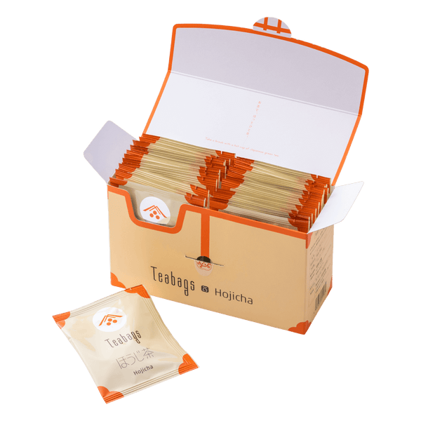 Open cream box containing 25 individually wrapped Hojicha Teabags beside one teabag packet with orange corners and Ippodo logo