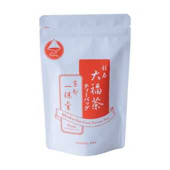 Pyramid shaped teabag of genmaicha green tea and roasted rice beside package of Obukucha Good Fortune Tea Teapot-Size Teabags