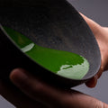 Vivid green smooth thick koicha Ippodo Premium Select Matcha sticking to sides of tilted black artisan-made ceramic tea bowl - thumbnail 4