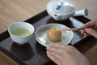 Front of of Ippodo Tea's flagship store, tearoom and headquarters black storefront in Kyoto, Japan with outdoor lit neon sign