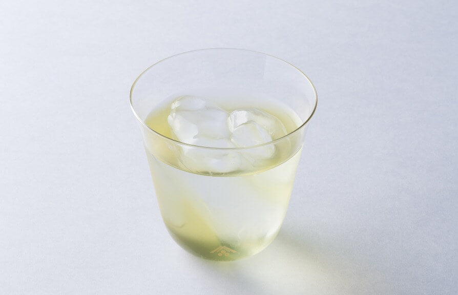 Small glass of light green Ippodo New Harvest sencha tea with ice cubes.